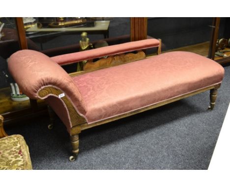 A late Victorian mahogany chaise longue, padded back rail, scrolling arm, stuffed overseat, turned legs, ceramic casters, cir