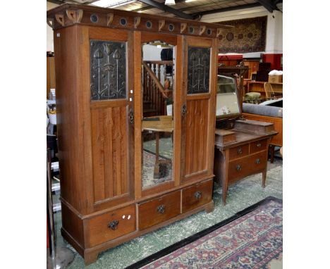 ***This is by Shapland and Petter of Barnstaple***An Arts and Crafts oak bedroom suite comprising triple wardrobe, outswept c