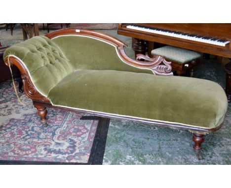 A Victorian mahogany chaise, shaped back rail, padded back, button upholstered scrolling arm, stuffed overseat, turned legs, 
