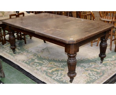 An oak wind out dining table, canted corners, turned and reeded supports, ceramic casters, circa 1830. one leaf. 75cm high x 