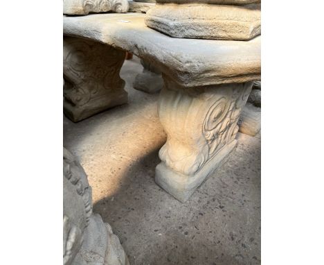 A curved concrete garden bench on scroll plinths  