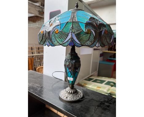 A Tiffany style table lamp with blue glass shade and  illuminated base.  