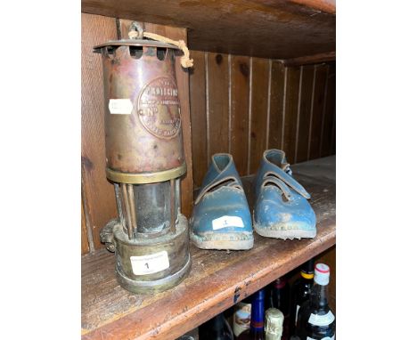 A pair of vintage clogs and a miner's pit lamp.  