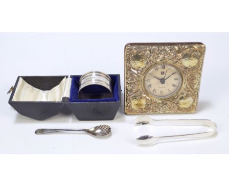 A cased hallmarked silver napkin ring, a pair of hallmarked silver sugar tongs, a single silver cruet spoon and a Quartz time