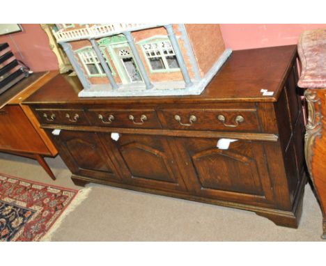 A reproduction oak sideboard with three drawers above three cupboard doors, on bracket feet, length 166cm.