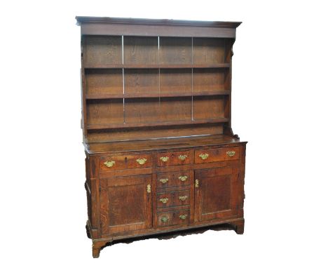 A late George III oak dresser with plate rack, the lower section with an arrangement of five short drawers and two cupboard d