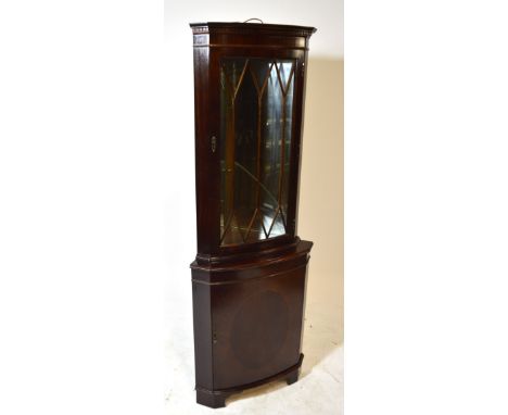 A reproduction mahogany and inlaid freestanding corner cupboard, the glazed upper section with mirrored interior above cupboa
