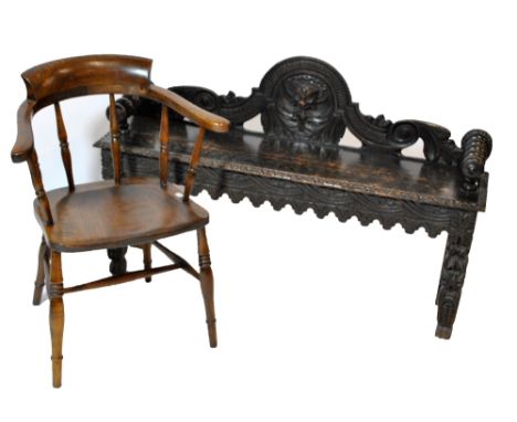 An oak window seat, the domed back carved with mask flanked by foliate scrolls and with bobbin turned handles, length 120cm, 