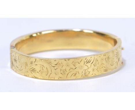 A 9ct yellow gold hinged snap bangle with upper panel engraved with flowers, internal width approx 6.1cm, approx 17.2g.