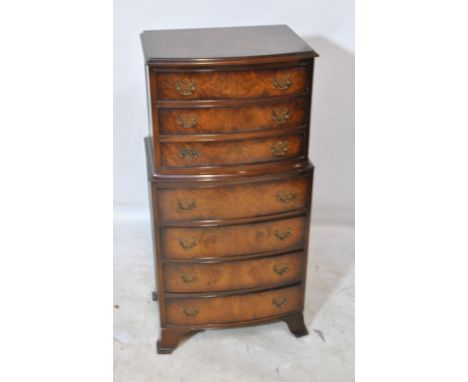 A reproduction walnut bowfronted chest on chest of small proportions, the upper section with three drawers above a base of fo