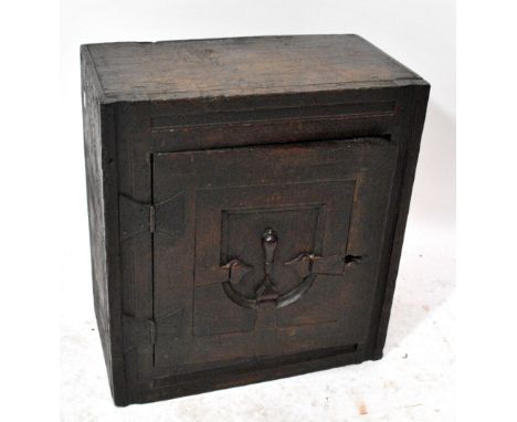 A 17th century oak spice cabinet, probably once part of a coffer, the single door with carved decoration enclosing a shelf, w