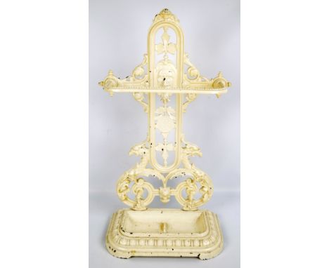 A late Victorian cream painted cast iron stick stand, decorated with a face, mythical creatures and floral and foliate motifs