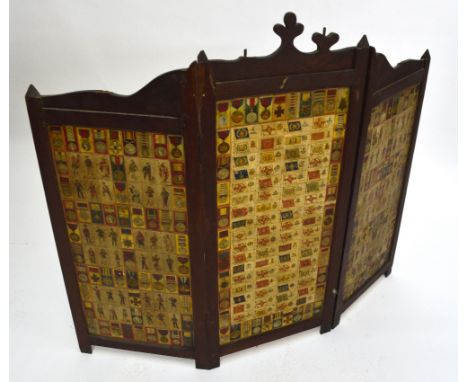 An early 20th century folding oak fire screen decorated with military cigarette cards, width when extended 122cm.