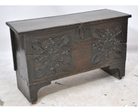 A 17th century oak coffer, the hinged lid above carved front and moulded bracket supports, width 102cm.