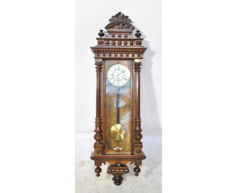 A large late 19th century eight days weight driven Vienna wall clock with ornamental pediment above circular two-piece dial s