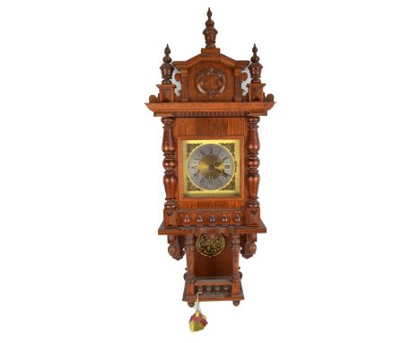 A German oak wall clock with raised pediment, silvered chapter ring set with Roman numerals and a boxed brass pendulum, heigh