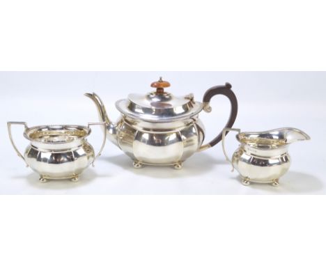 ISRAEL SIGMUND GREENBERG; a George V hallmarked silver three piece tea set, comprising a faceted oval teapot with C-scroll ha