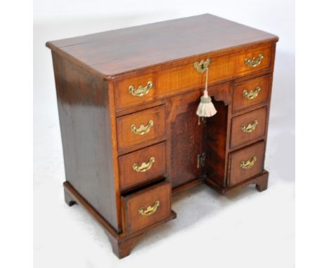 An 18th century walnut kneehole pedestal desk, the recessed central cupboard enclosing single shelf flanked by three short dr