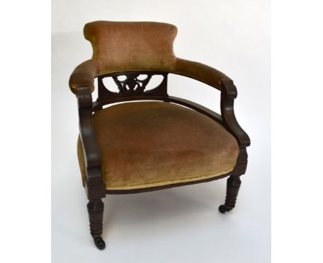 A late Victorian mahogany and upholstered tub chair with ring turned front supports to castors.