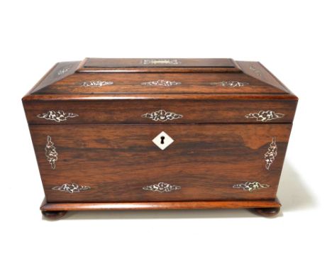 A William IV rosewood tea caddy of sarcophagus form with mother of pearl inlaid stylised floral motifs, the hinged lid enclos