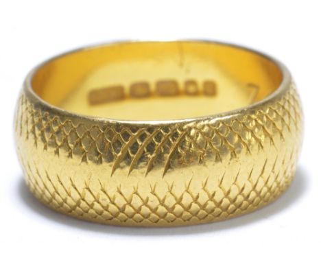 A 22ct yellow gold wedding band with textured decoration, size K, approx 7.2g.
