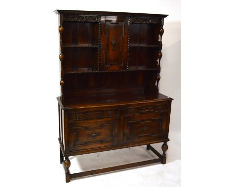 An early 20th century oak Jacobean style dresser with boarded plate rack centred with cupboard doors above two drawers and pa
