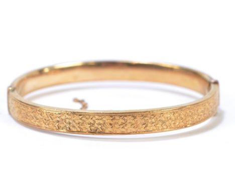 A 9ct yellow gold hinged bangle with engraved detail to one half (safety chain af), approx 9g.