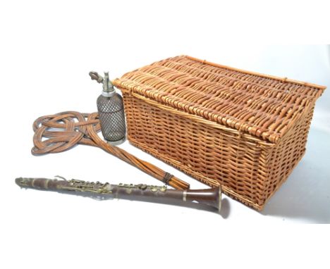 A wicker picnic basket, a carpet beater, a clear glass wirework covered syphon and a resin clarinet.