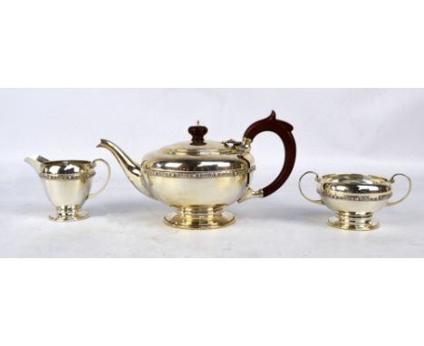 CHARLES S GREEN & CO LTD; an Elizabeth II hallmarked silver three piece tea set, comprising a squat circular teapot with C-sc