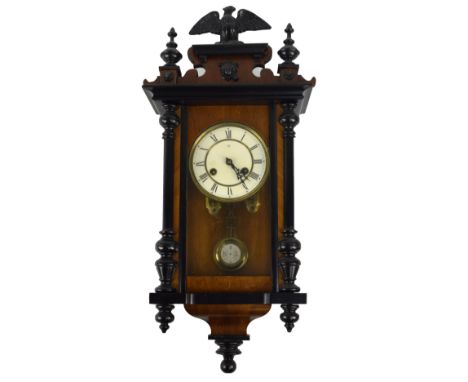 A late 19th century walnut and ebonised Vienna style wall clock of small proportions with two piece white enamel dial set wit