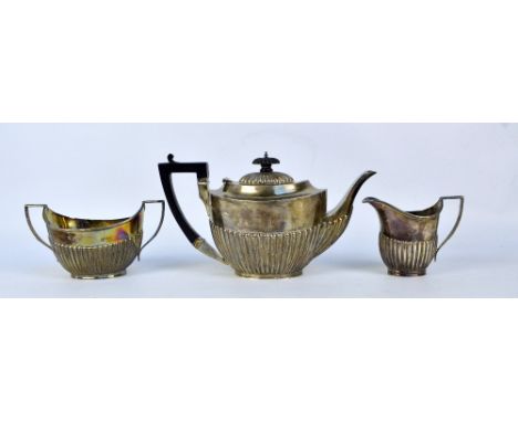 A matched hallmarked silver part gadrooned tea set, comprising oval teapot with ebony handle and finial, James Deakin & Sons,