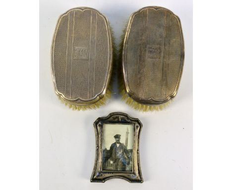 DANIEL MANUFACTURING CO; a pair of George V hallmarked silver coat brushes with engine turned decoration and initialled 'HCB'