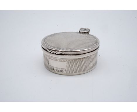 An Elizabeth II silver pill box, of drum form, guilloche engraved, and bright-cut engraved with a stylized foliate border to 