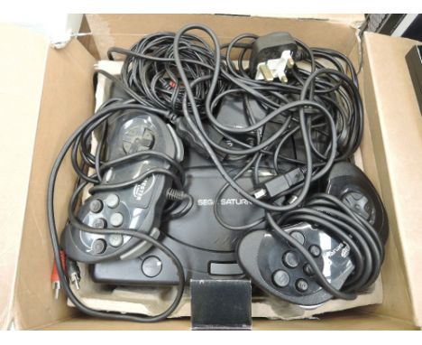 A Sega Saturn games console with two controllers in original box with cables along with a steering wheel and games