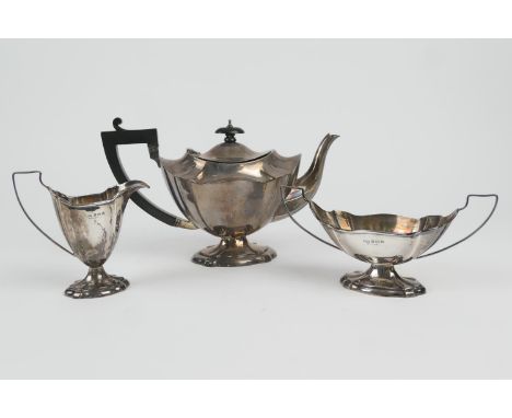 George V silver three piece tea service, Birmingham 1926, comprising teapot of footed and fluted oval section, with ebony fin