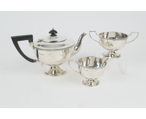 George V silver three piece tea service by Walker &amp; Hall, Sheffield 1932/33, comprising footed U-shaped teapot with ebony