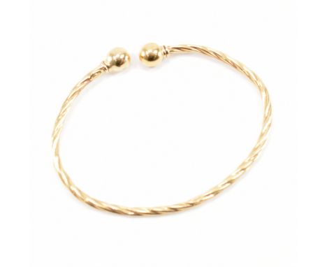 A hallmarked 9ct yellow gold torque bangle. The bracelet having a twist effect shank with ball finials. Hallmarked for Sheffi
