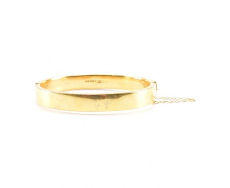 A 9ct gold Birmingham hallmarked bangle complete with safety chain. Hollow cast, Birmingham hallmarks, date letter b, sponsor
