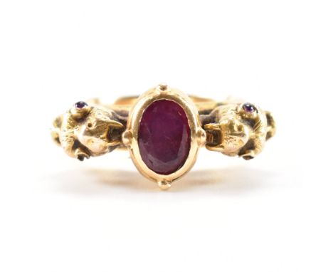 A 19th Century Victorian gold and ruby dragon head ring. The ring being set with an oval cut ruby flanked by moulded dragon h