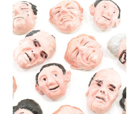 A collection of grotesque portrait brooch pins. The brooches depicting various caucasian male faces in a plethora of facial e