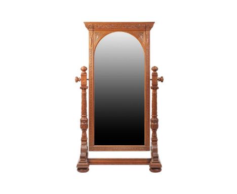 A large late Victorian carved oak cheval dressing mirror with scroll cornicing above an arched bevelled mirror plate and stop