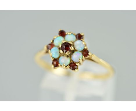 A 9CT GOLD OPAL AND GARNET CLUSTER RING designed as a central circular garnet within an opal cabochon surround and further ou