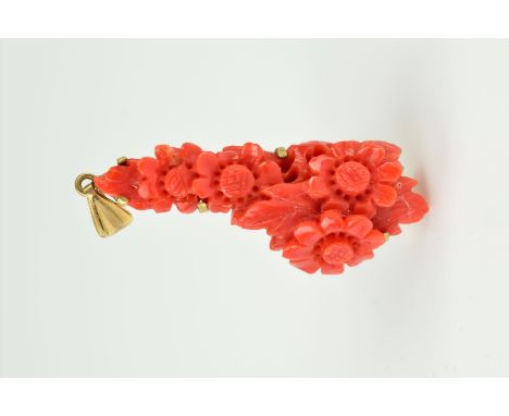 A DYED CARVED CORAL 9CT GOLD PENDANT of elongated outline, the coral carved to depict flowers and leaves, claw set to the 9ct