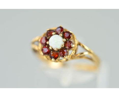 A 9CT GOLD OPAL AND GARNET RING, designed as a central circular opal cabochon within a circular garnet surround to the open s