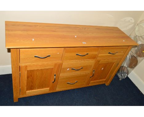 A MODERN LIGHT OAK SIDEBOARD with five various drawers and double cupboard doors, width 138cm x depth 43cm x height 77cm