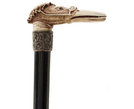 A LATE 19TH CENTURY WALKING STICK, the ivory handle carved as the head of a duck wearing bonnet and glasses, above foliate em