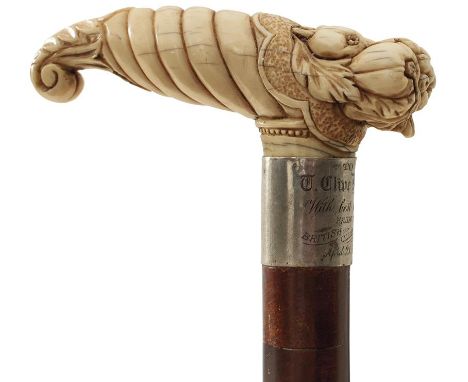 AN EARLY 20TH CENTURY WALKING STICK, the ivory handle carved as a cornucopia of fruits, above white metal collar engraved TO 