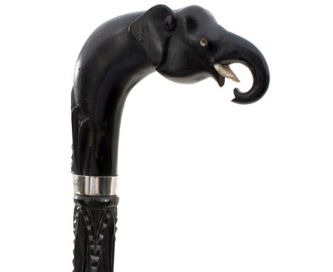 A CARVED EBONY WALKING STICK WITH ELEPHANT'S HEAD HANDLE, inset with bone dot decoration and foliate and geometric carved ove