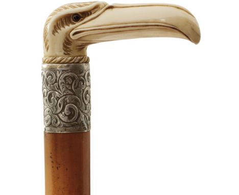 A LATE 19TH CENTURY WALKING STICK, the ivory handle carved as a stylised eagle's head, above white metal collar engraved JW J