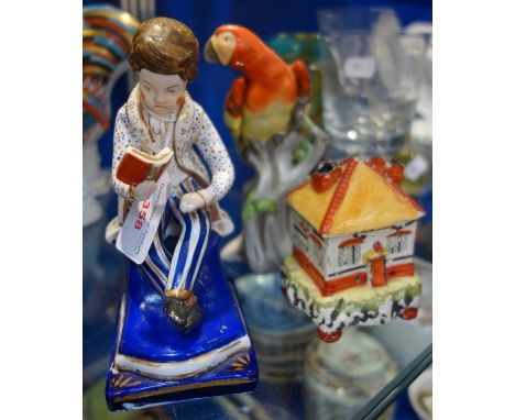 A 19TH CENTURY CONTINENTAL STUDY OF A BOY READING, 16cm high, a pastille burner in the form of a house and a ceramic parrot (